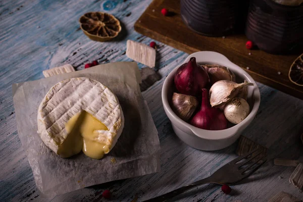 Queijo camembert quente sobre tábua de madeira com alho e cebola — Fotografia de Stock