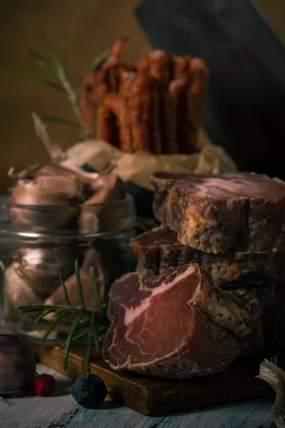 イタリア イノシシとニンニクがガラスのまな板の上からの乾燥してスモークした肉 — ストック写真