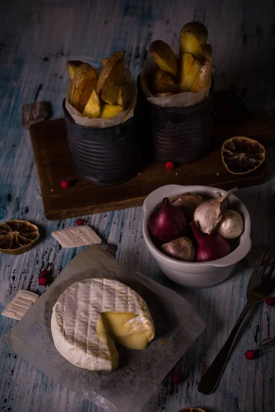 Queijo de camembert derretido em tábua de madeira com cebolas e tiras de batata fritas — Fotografia de Stock