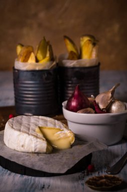 Soğan ve kızarmış patates yapmana ahşap tahta üzerinde erimiş sıcak camembert peyniri