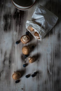 Çanta ahşap tahta üzerinde kahverengi kapaklar ile birkaç mantar üzerinde üstten görünüm döktüm