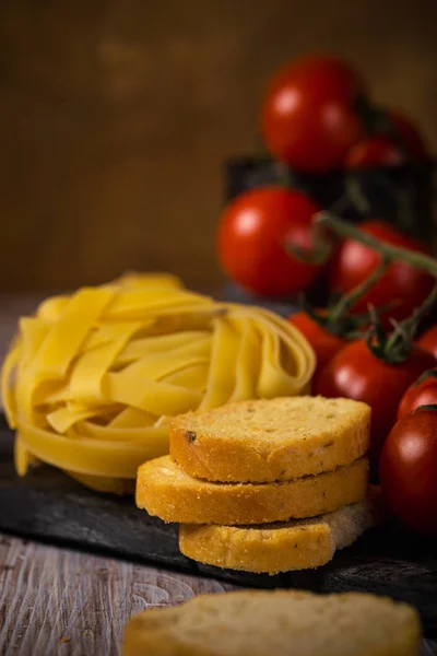 Pochi pezzi di bruschetta accanto a tagliatelle e pomodorini — Foto Stock