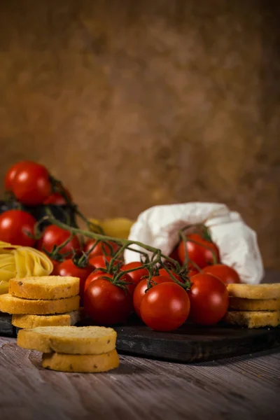 Small cherry tomatoes on several twigs with bruschetta — Stock Photo, Image