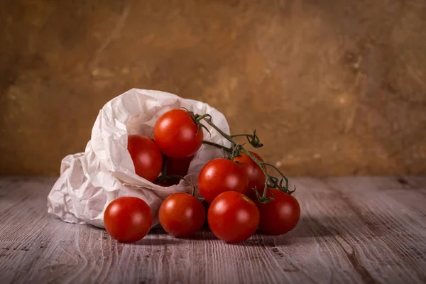 Jugosos tomates rojos frescos sobre tabla de madera en bolsa de papel —  Fotos de Stock