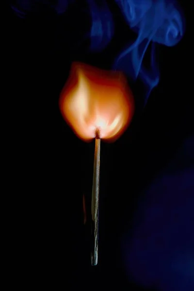 Safety match on black background with flaming head