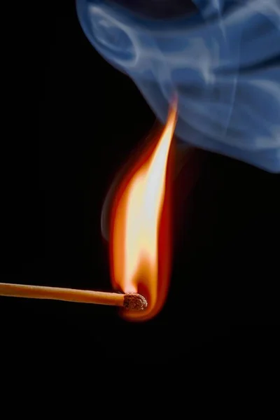 Safety match on black background with flaming head