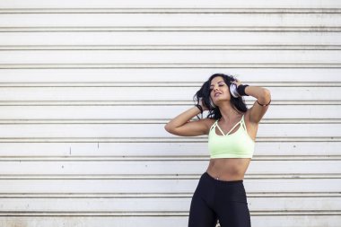 Kadın kulaklıkları boynunda koştuktan sonra rahatlıyor.