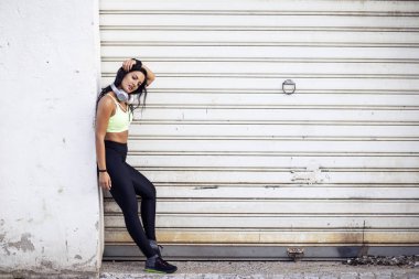 Kadın kulaklıkları boynunda koştuktan sonra rahatlıyor.