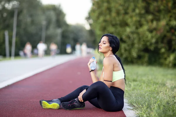 Jogging woman sitting and relax on ground