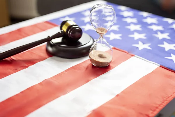 United states flag with wooden gavel and hourglass on it — ストック写真