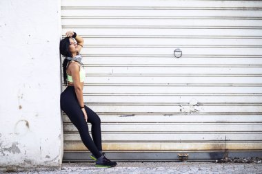 Jog woman with headphones posing in front of white door