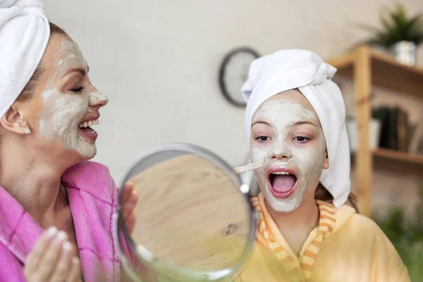 Mother with dauhtrer with facial mask of natural ingredients feeling happy at home