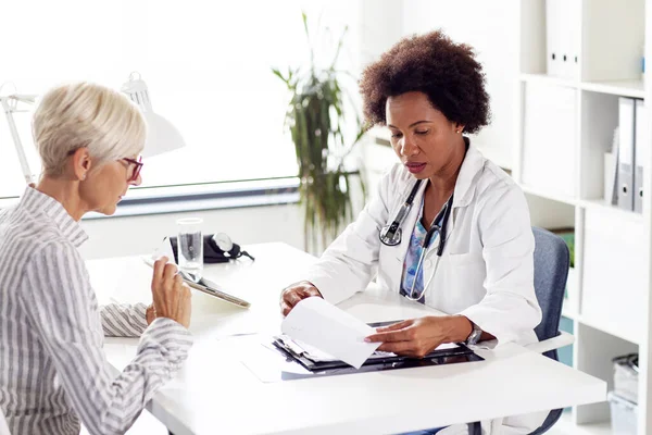 Looking at results of treatment mature woman in ambulance with her doctor