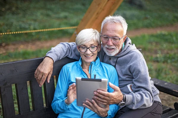 Casal sênior com tablet em parque público — Fotografia de Stock