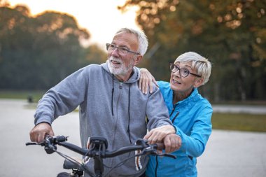Halk parkında bisikleti olan yaşlı bir çift.