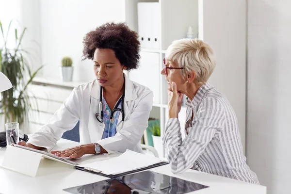 Looking at results of treatment mature woman in ambulance with her doctor