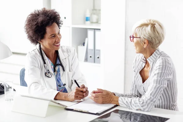 Olgun kadın doktoruyla klinikteki sağlık hakkında konuşuyor.