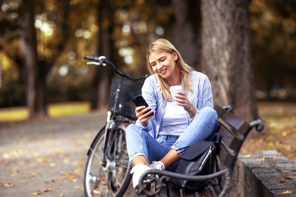 의자에 핸드폰을 커피를 마시며 자전거를 공원에 스톡 이미지