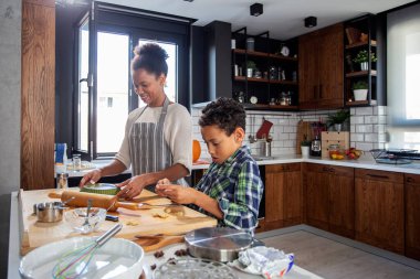 Mutfakta çocuklu annem kurabiye yapıyor.