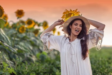 Gün sonunda ayçiçeği tarlasının önündeki kadın.