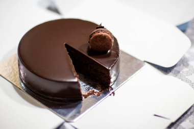Chocolate cake in a white and silver box with a chocolate macaroon on the top