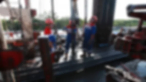 Petrol işçilerinin bulanık görüntüsü yağ pompasını kontrol ediyor. Bir petrol kuyusu bakım platformunda pis ve tehlikeli işler yapan aylaklar..