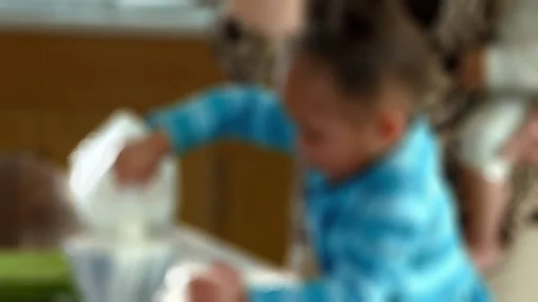 Bulanık görünümlü Afro-Amerikan kız bir kaseye süt döküyor. Arka planda süt içecekleri reklamı var.