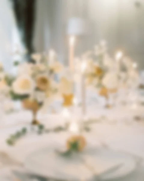 Blurred view of Wedding table and flower bouquet center piece with table settings.fit for wedding articles background.