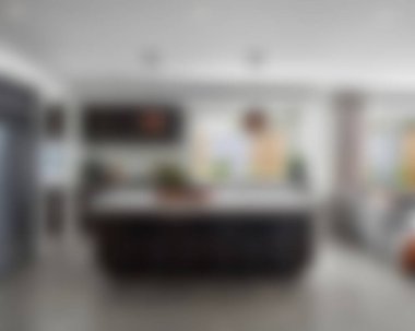 Ada, granit tezgah, paslanmaz çelik buzdolabı, fırın ve ahşap zemini olan çağdaş beyaz bir mutfağın içi.