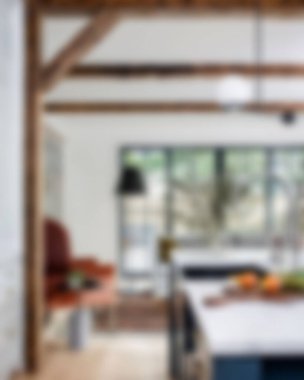 Ada, granit tezgah, paslanmaz çelik buzdolabı, fırın ve ahşap zemini olan çağdaş beyaz bir mutfağın içi.