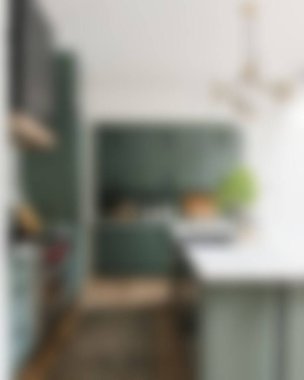 Ada, granit tezgah, paslanmaz çelik buzdolabı, fırın ve ahşap zemini olan çağdaş beyaz bir mutfağın içi.