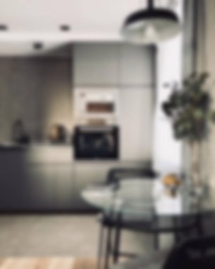 Ada, granit tezgah, paslanmaz çelik buzdolabı, fırın ve ahşap zemini olan çağdaş beyaz bir mutfağın içi.