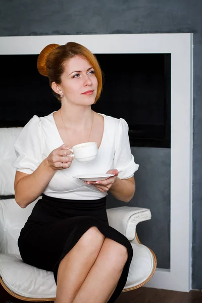 Jonge vrouw drinkt koffie op kantoor — Stockfoto