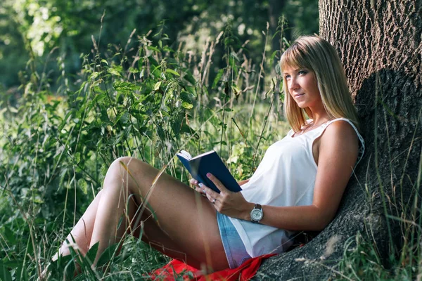Portret van de jonge vrouw zittend onder een boom — Stockfoto