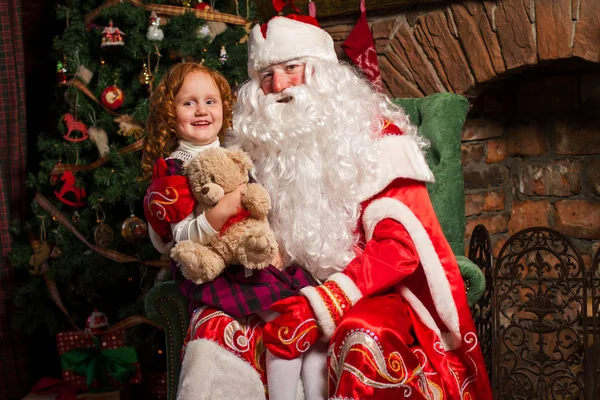 Санта Клаус сидит в кресле с маленькой девочкой . — стоковое фото