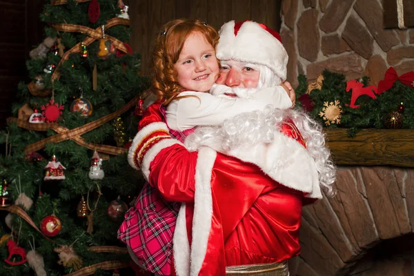 Santa Claus håller på händer glad liten tjej. — Stockfoto