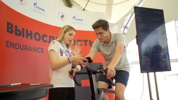 Misk, Belarus - 21 juni 2019 Jongeman doet een test op een hometrainer onder begeleiding van een instructeur — Stockvideo