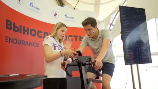 Misk, Belarus - 21 de junho de 2019 Jovem faz um teste em uma bicicleta de exercício supervisionada por um instrutor — Vídeo de Stock