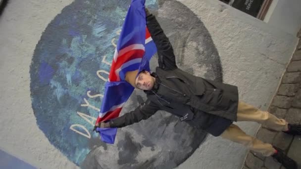 REYKJAVIK, ISLANDIA, 10 de octubre de 2019 Un tipo con la bandera de Islandia sobre un fondo de graffiti en Reykjavik — Vídeos de Stock