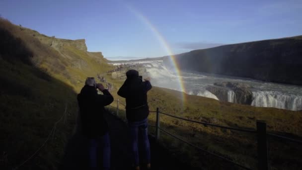 2019年10月10日，冰岛雪兰，REYKJAVIK，伙计们在冰岛的Gullfoss瀑布上拍下彩虹的照片 — 图库视频影像
