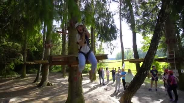 SILICHY, BELARUS - 2, AUGUST, 2019: Een meisje op een kabel daalt af van een boom. Touwpark — Stockvideo