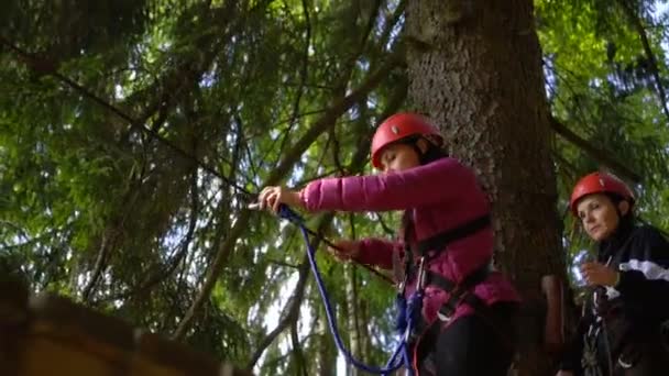 SILICHY, BELARUS - 2, AĞUSTOS, 2019: tırmanma eğitimi. Kırmızı kasklı kızlar güvenlik ipine sarılıp halat parkından geçiyorlar. — Stok video