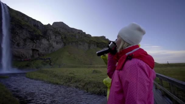 Çocuklar kahve içip Seljalandsfoss şelalesinin tadını çıkarıyorlar. — Stok video