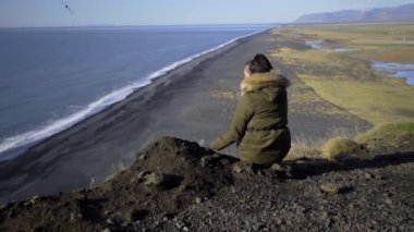 Bir kız uçurumun kenarında oturur ve denize bakar. Bir kuş uçurumdan uçar