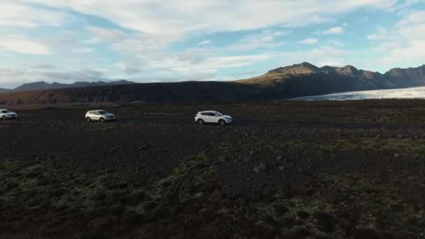 Čtyři džípy na štěrkové cestě mezi horami a ledovcem. Cestování přes hory a ledovce Islandu — Stock video