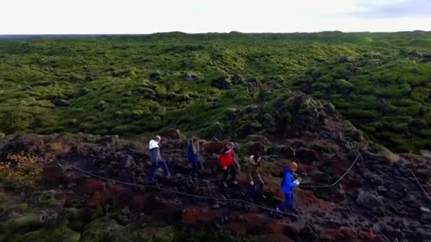 Skupina lidí se pohybuje po lávových polích pokrytých mechem. Zelený mech na lávovém poli — Stock video