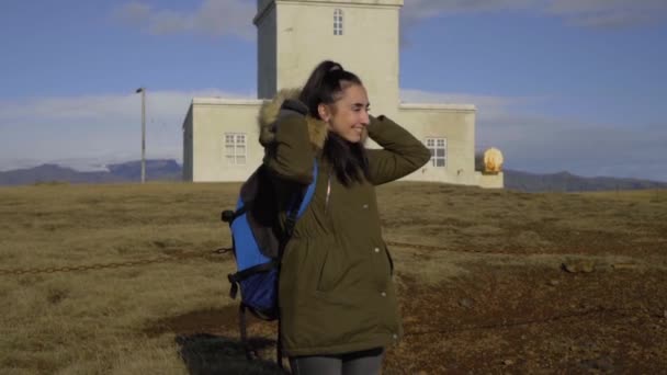 Une fille met une capuche en fourrure près d'un phare blanc et sourit — Video