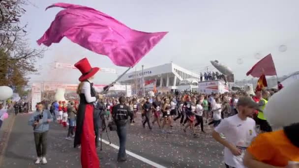 MINSK, BELARUS- 2019年9月15日:旗を持った男がハーフマラソンの参加者を迎えます。スポーツイベントでのお祭りの雰囲気 — ストック動画