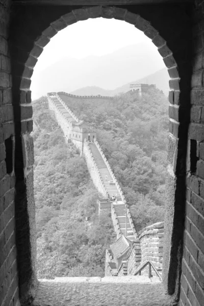 Büyük duvar bir nöbetçi kulübesinden izledi. Gözetleme noktasından bir kapı tarafından çerçevelenmiş. Merdivenler büyük bir dengesizliği koruyor. Mutianyu bölümü, Pekin, Çin. Siyah beyaz fotoğraf. — Stok fotoğraf
