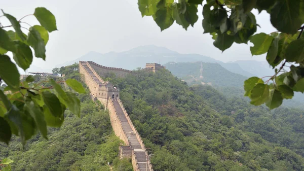 La gran muralla salva un enorme desnivel, enmarcado por algunas hojas. Caminata a través de la gran pared. Sección Mutianyu, Pekín, China — Foto de Stock
